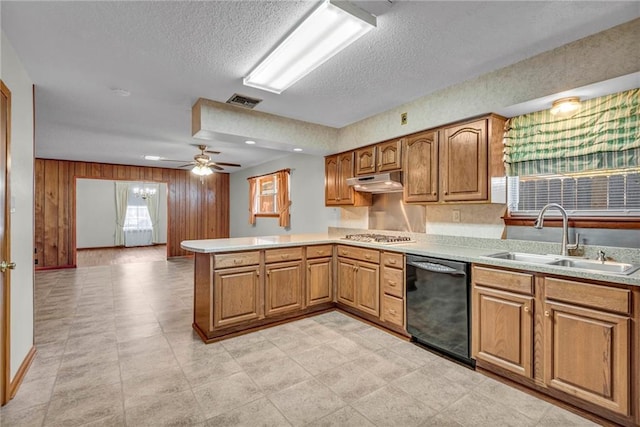 kitchen featuring sink, black dishwasher, kitchen peninsula, wood walls, and a textured ceiling