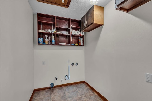 washroom with hookup for a gas dryer, light tile patterned flooring, cabinets, and a textured ceiling