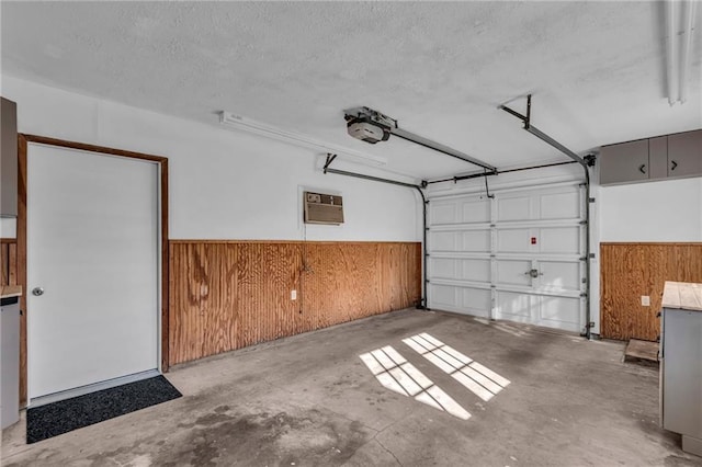 garage with a garage door opener, an AC wall unit, and wood walls