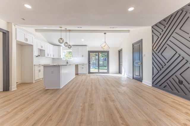 kitchen with white cabinets, pendant lighting, lofted ceiling with beams, and light hardwood / wood-style flooring