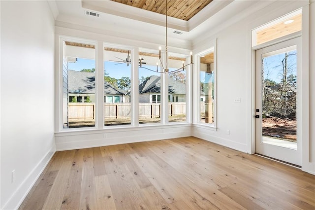 unfurnished sunroom featuring a tray ceiling and a chandelier