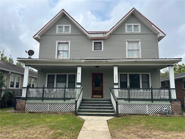 view of front of house with metal roof, a porch, and a front yard