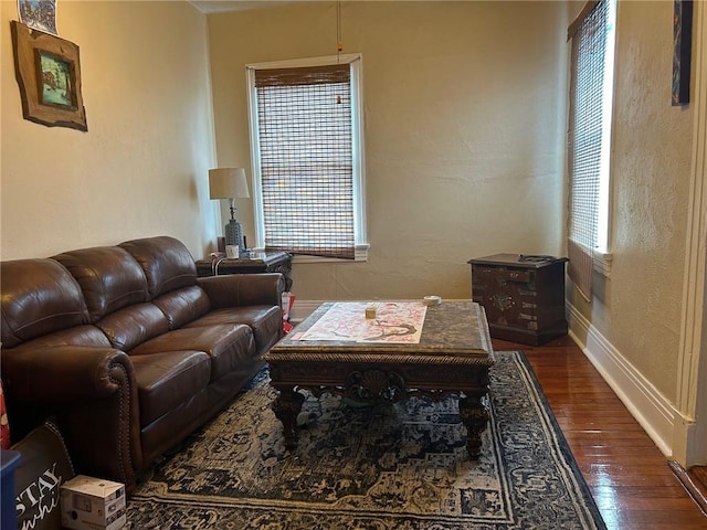 living area featuring baseboards, dark wood-style floors, and a textured wall