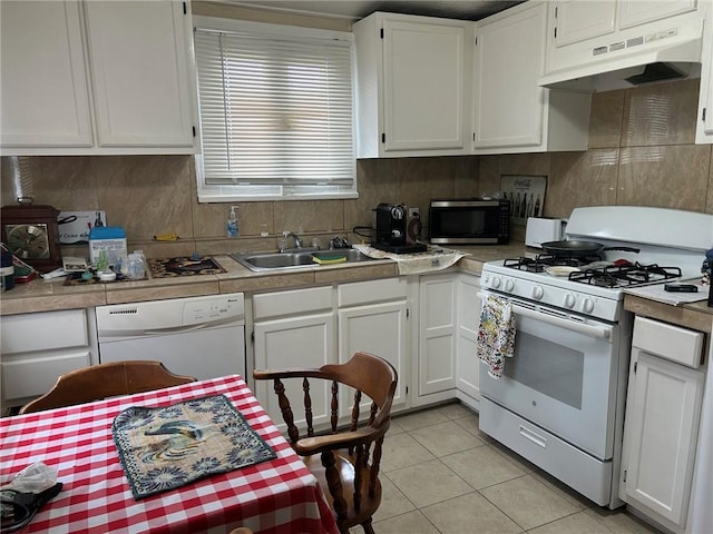 kitchen featuring under cabinet range hood, decorative backsplash, white appliances, and a sink