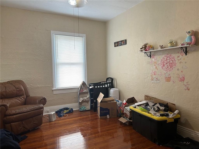 rec room featuring baseboards, wood-type flooring, and a textured wall