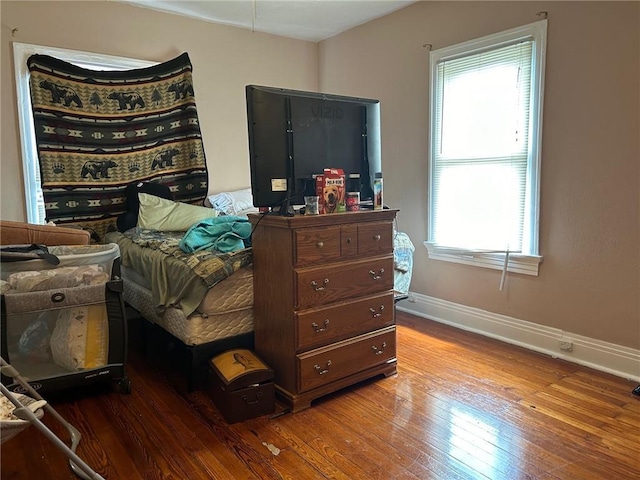 bedroom featuring multiple windows, baseboards, and wood-type flooring