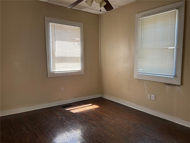 unfurnished room featuring dark wood-style floors, a ceiling fan, and baseboards