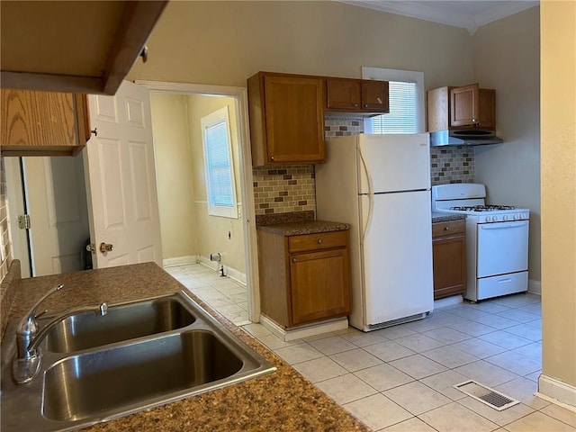 kitchen featuring visible vents, backsplash, brown cabinetry, white appliances, and a sink