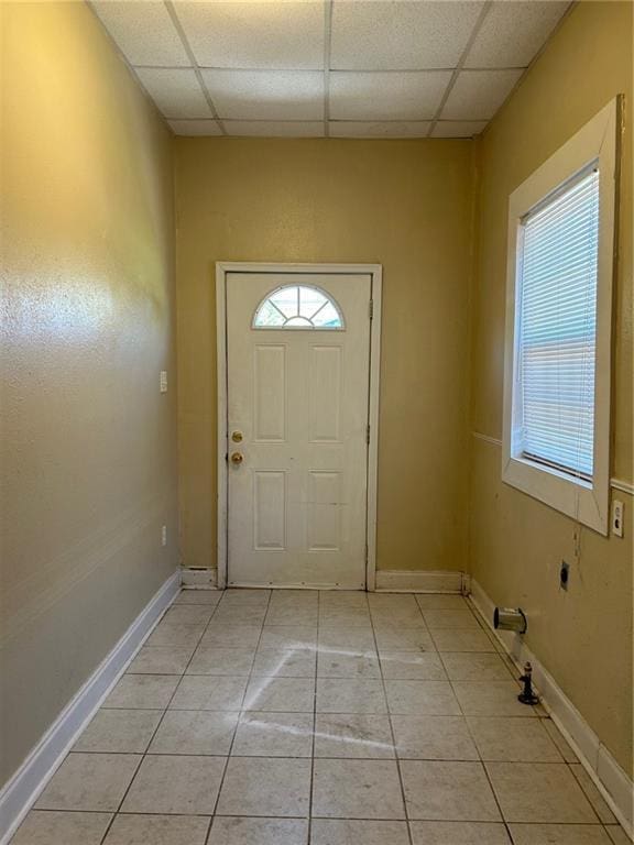 entryway featuring light tile patterned floors, a paneled ceiling, and baseboards