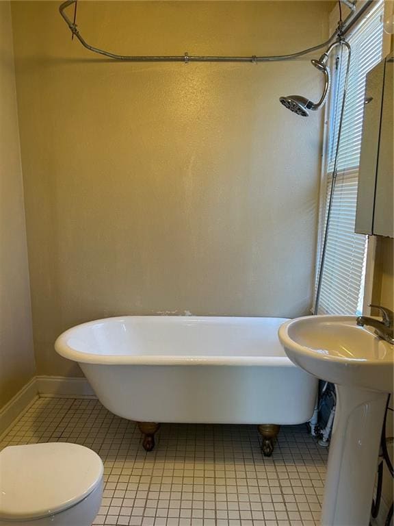 full bathroom featuring baseboards, toilet, a freestanding bath, tile patterned floors, and a shower