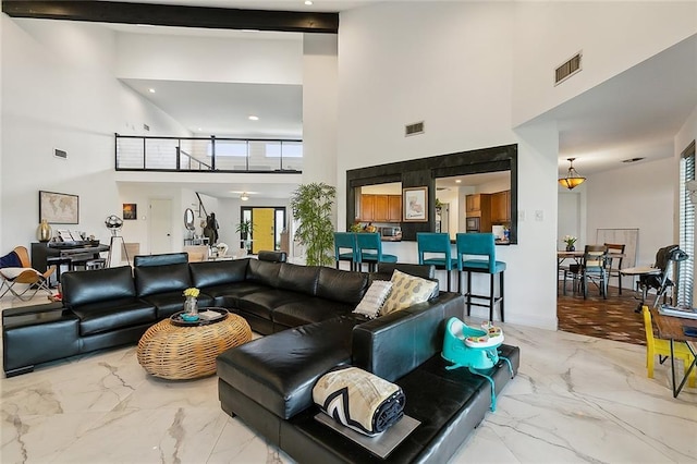 living room with beamed ceiling and a high ceiling