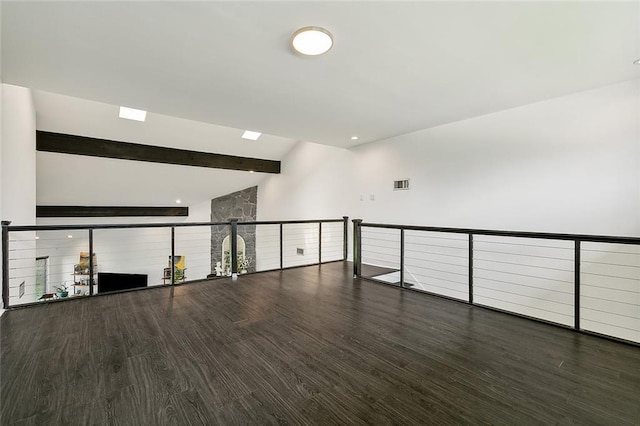 empty room with beamed ceiling and dark hardwood / wood-style floors