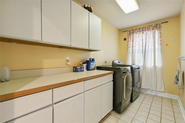 clothes washing area featuring cabinets, washer and clothes dryer, and light tile patterned flooring