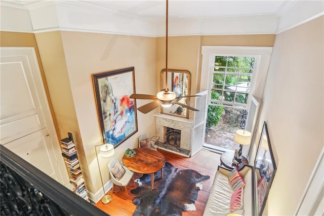 living room featuring a fireplace, hardwood / wood-style flooring, ceiling fan, and ornamental molding