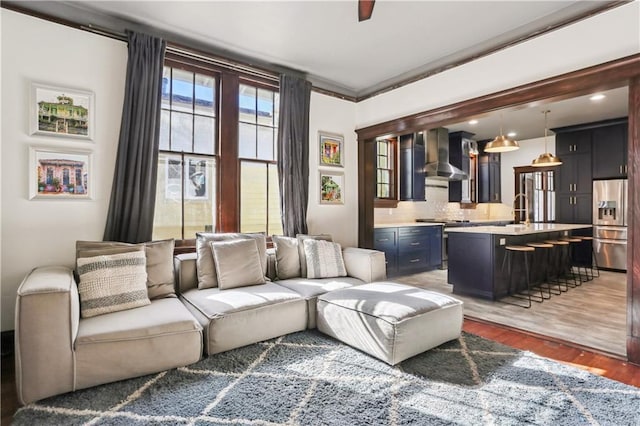 living room with ceiling fan, sink, dark wood-type flooring, and ornamental molding