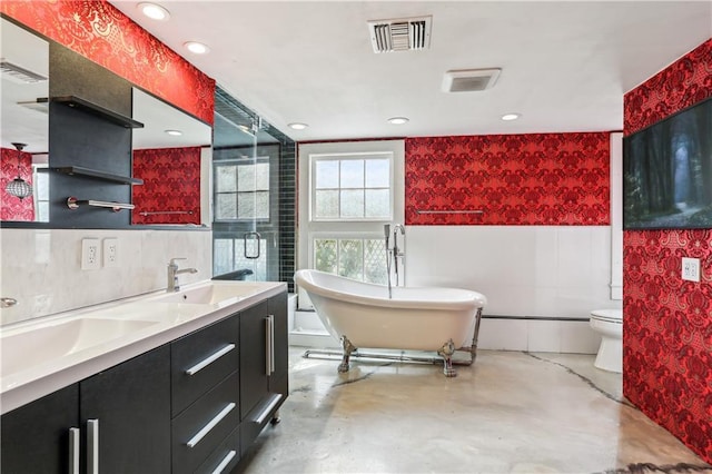 bathroom featuring a bathing tub, vanity, toilet, and concrete floors