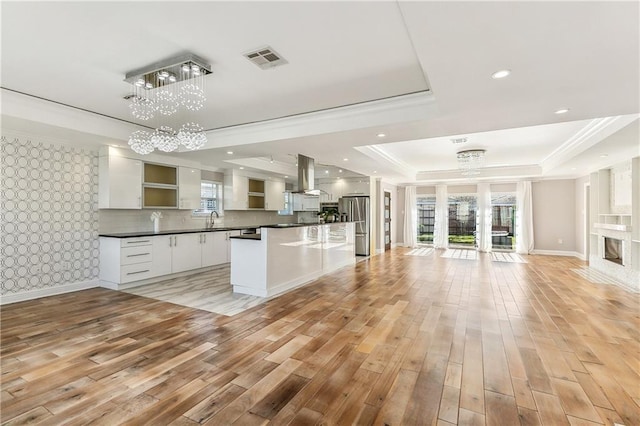 kitchen with white cabinets, pendant lighting, light hardwood / wood-style floors, and a raised ceiling