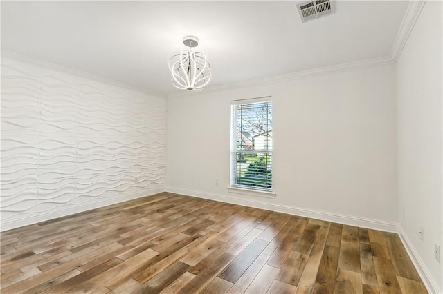 empty room featuring wood-type flooring, a notable chandelier, and ornamental molding