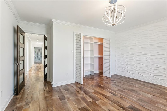 unfurnished bedroom featuring a notable chandelier, dark hardwood / wood-style floors, crown molding, and a closet