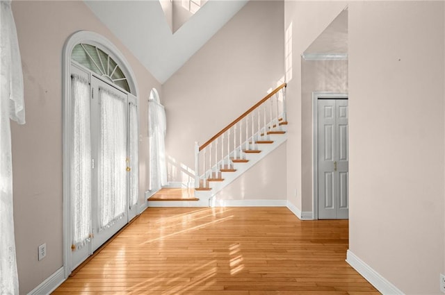 foyer entrance with hardwood / wood-style floors, high vaulted ceiling, and a wealth of natural light