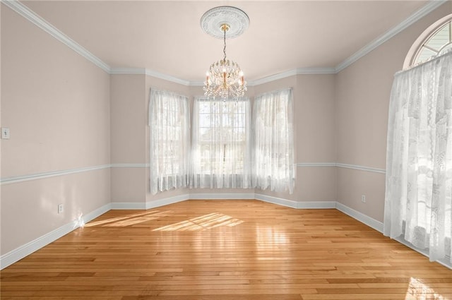 spare room featuring a notable chandelier, ornamental molding, and light hardwood / wood-style flooring