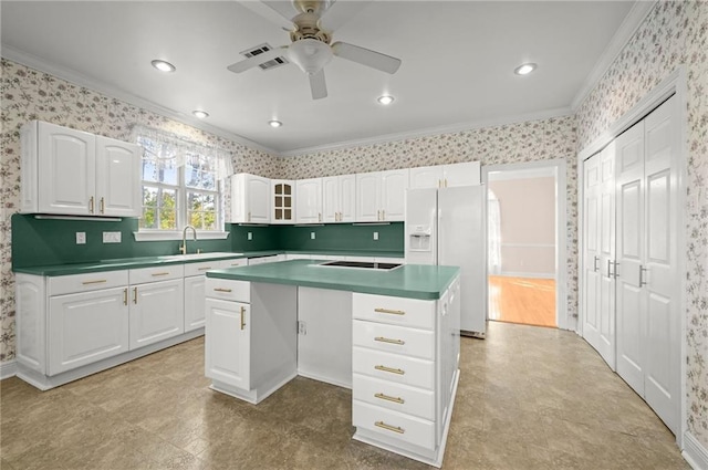 41298 Baytown Rd, Hammond, LA 70403 - kitchen featuring crown molding, a ceiling fan, white refrigerator with ice dispenser, white cabinetry, and wallpapered walls