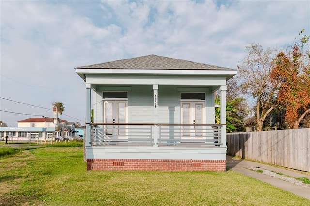 rear view of property featuring a lawn and covered porch