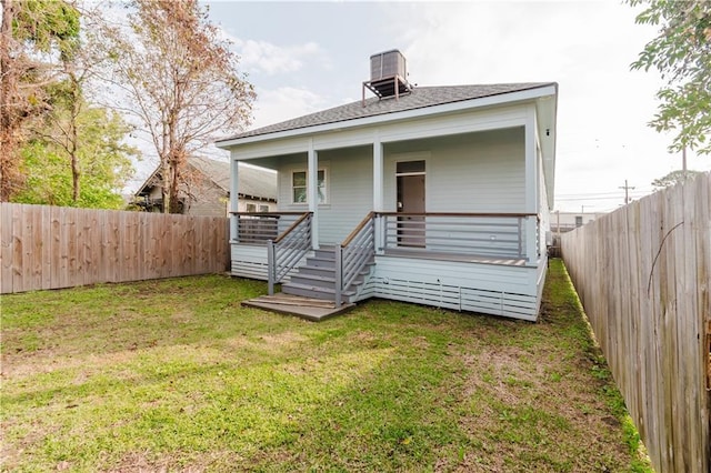 rear view of house featuring central air condition unit and a yard