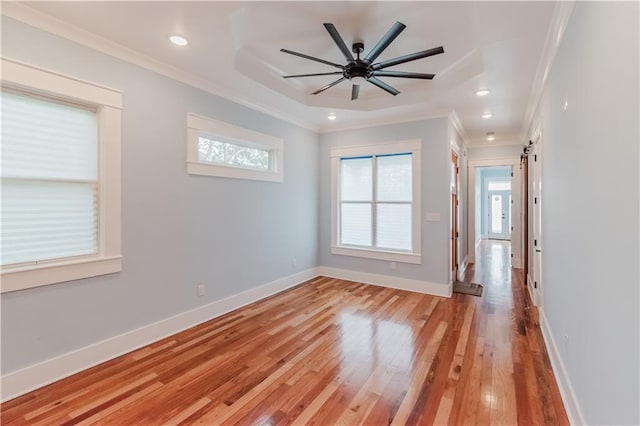 spare room with a barn door, ceiling fan, ornamental molding, and light wood-type flooring