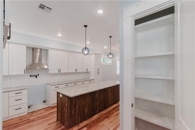 kitchen featuring white cabinetry, a center island, wall chimney exhaust hood, and light hardwood / wood-style flooring