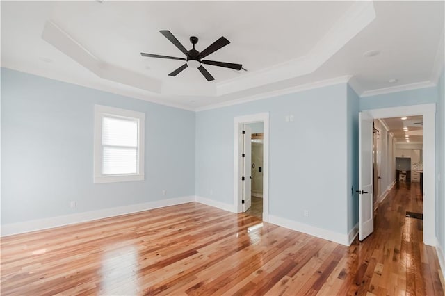 empty room featuring light hardwood / wood-style floors, a raised ceiling, ceiling fan, and crown molding