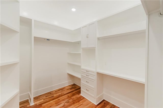 walk in closet featuring light hardwood / wood-style flooring and built in desk