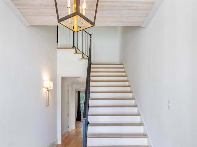 stairs with a chandelier, hardwood / wood-style floors, and wood ceiling