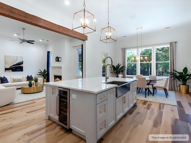 kitchen featuring a sink, beverage cooler, light wood-style floors, an inviting chandelier, and gray cabinetry