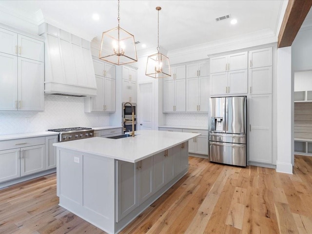 kitchen featuring decorative backsplash, stainless steel appliances, light countertops, premium range hood, and visible vents