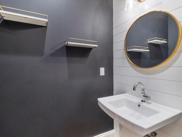 bathroom featuring a sink and wooden walls