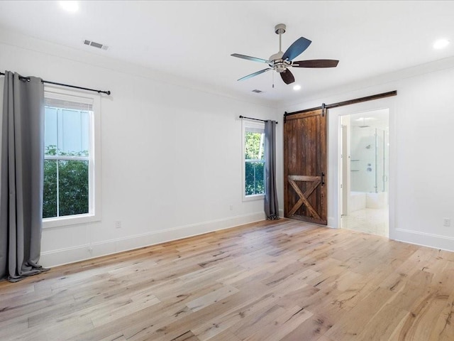 unfurnished room with a barn door, wood finished floors, ceiling fan, baseboards, and recessed lighting