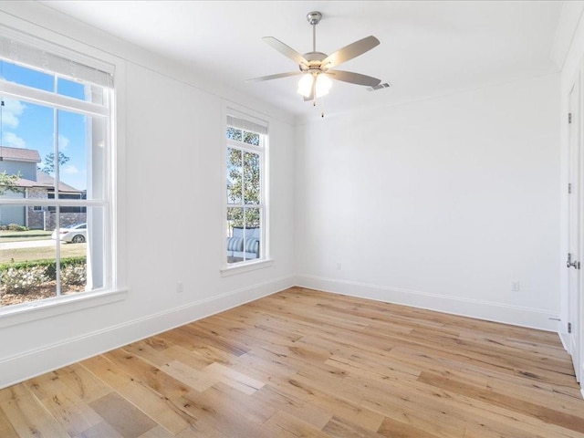 empty room featuring a ceiling fan, light wood-style flooring, visible vents, and baseboards