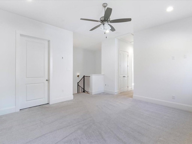 spare room with light carpet, a ceiling fan, and baseboards