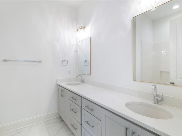 full bathroom with marble finish floor, double vanity, a sink, and baseboards