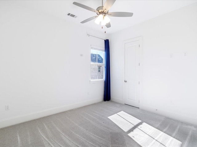 empty room with a ceiling fan, light colored carpet, visible vents, and baseboards