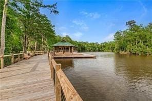 dock area with a gazebo, a wooded view, and a water view