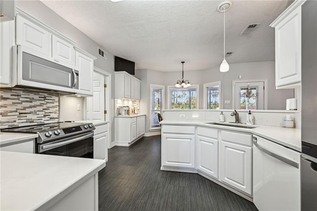 kitchen with sink, hanging light fixtures, stainless steel appliances, a notable chandelier, and white cabinets