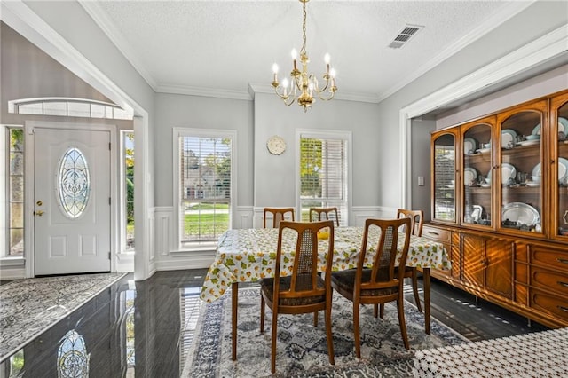 dining room with a textured ceiling, crown molding, dark wood-type flooring, and an inviting chandelier