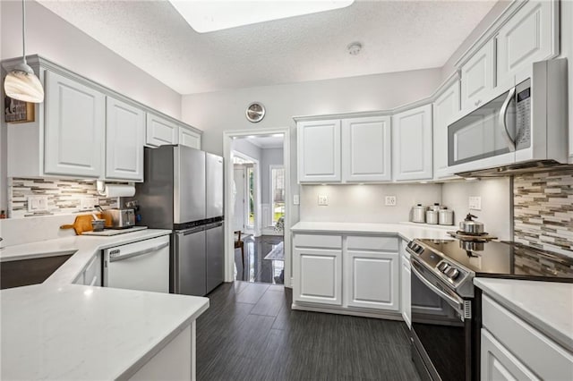 kitchen with white cabinets, appliances with stainless steel finishes, decorative backsplash, and hanging light fixtures