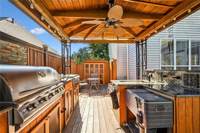 wooden terrace featuring a gazebo, an outdoor kitchen, grilling area, and ceiling fan