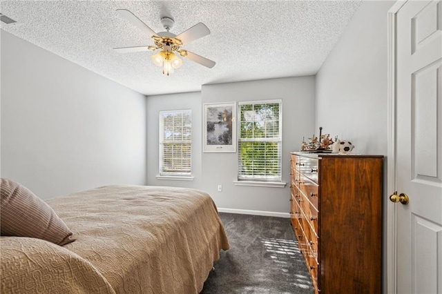 bedroom with ceiling fan, dark carpet, and a textured ceiling