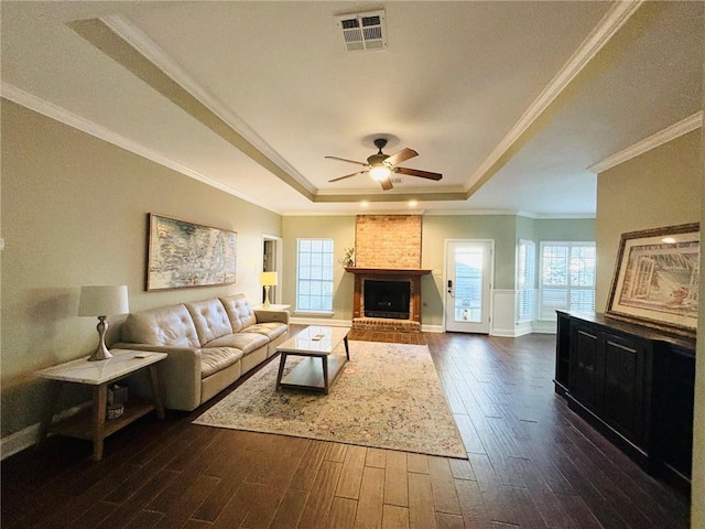 living room with a raised ceiling, a wealth of natural light, and dark hardwood / wood-style floors