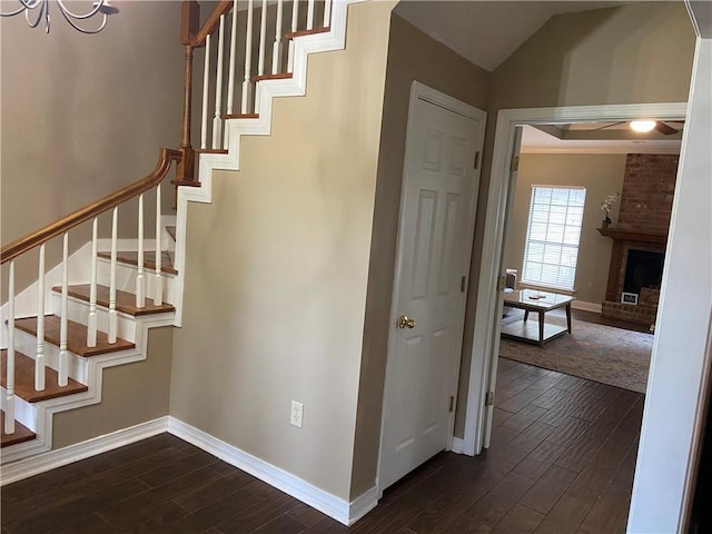 stairs with a fireplace, hardwood / wood-style floors, an inviting chandelier, and lofted ceiling