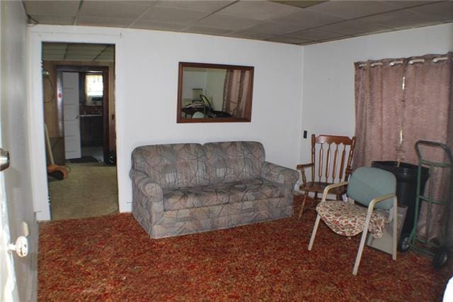 living room with a paneled ceiling and carpet